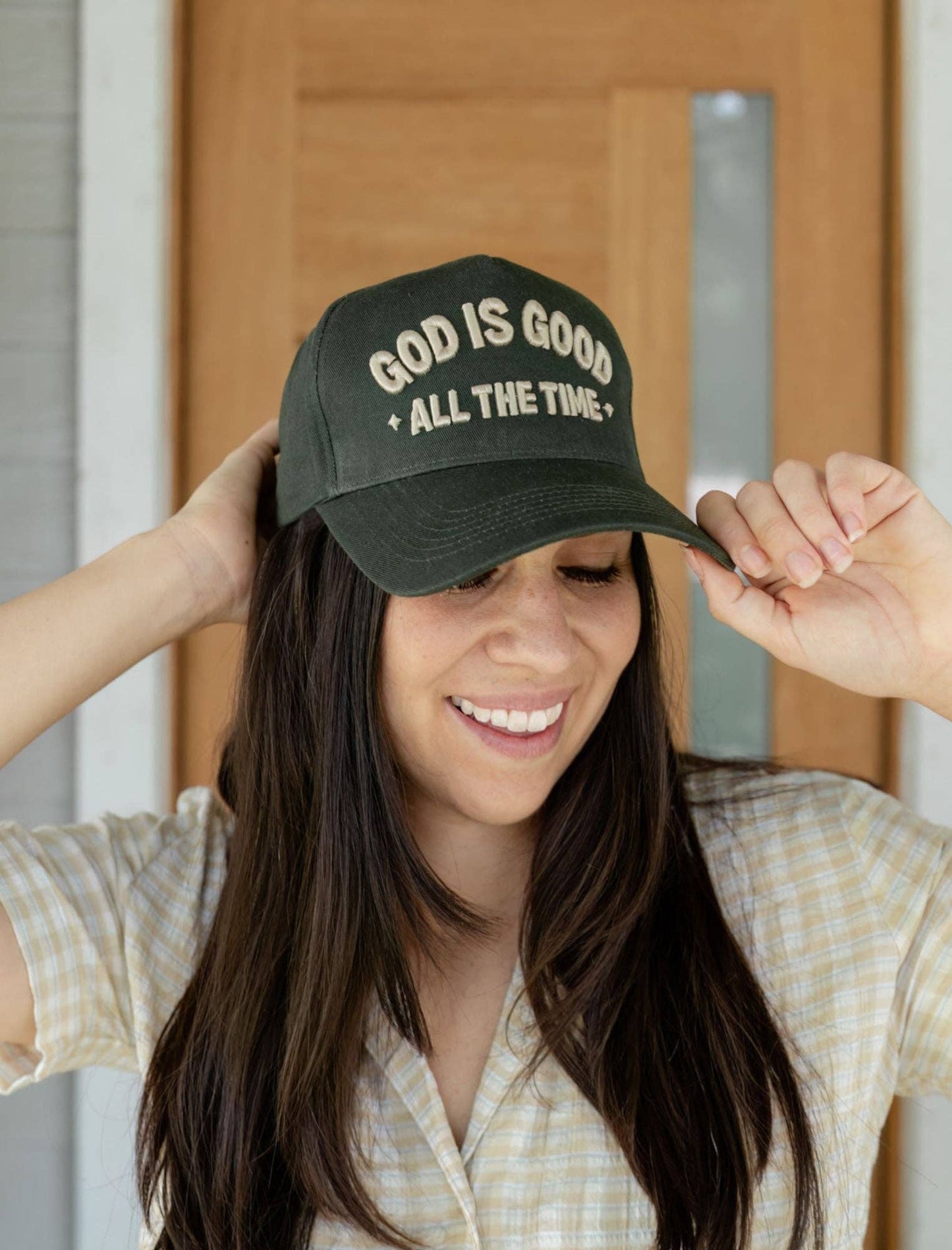 Person wearing a green cap with 'God is Good All the Time' text.