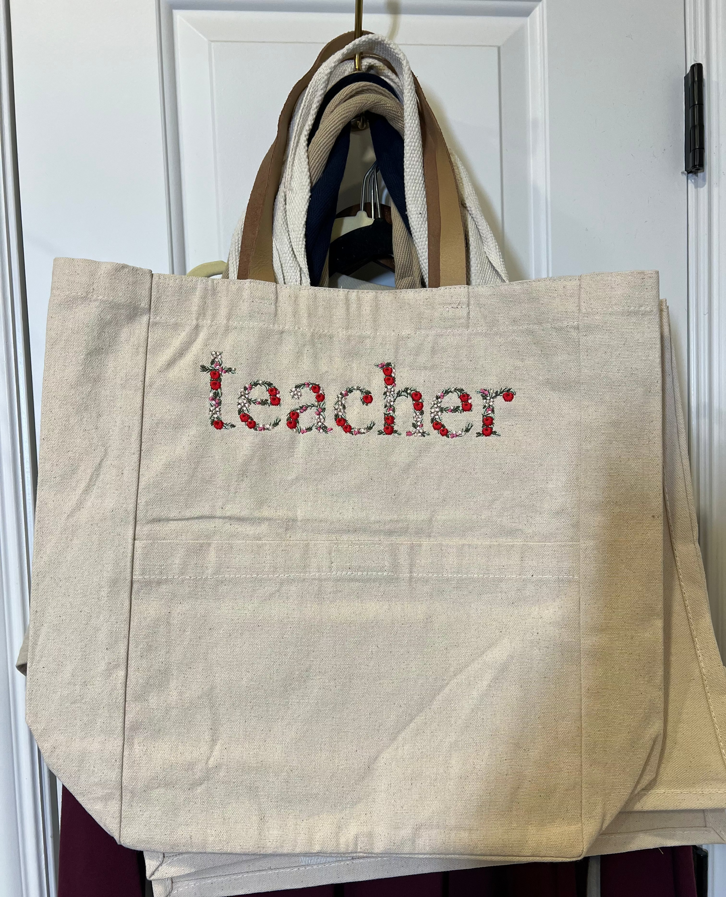 Teacher in Floral /Apple Font embroidered on the front of a tote bag