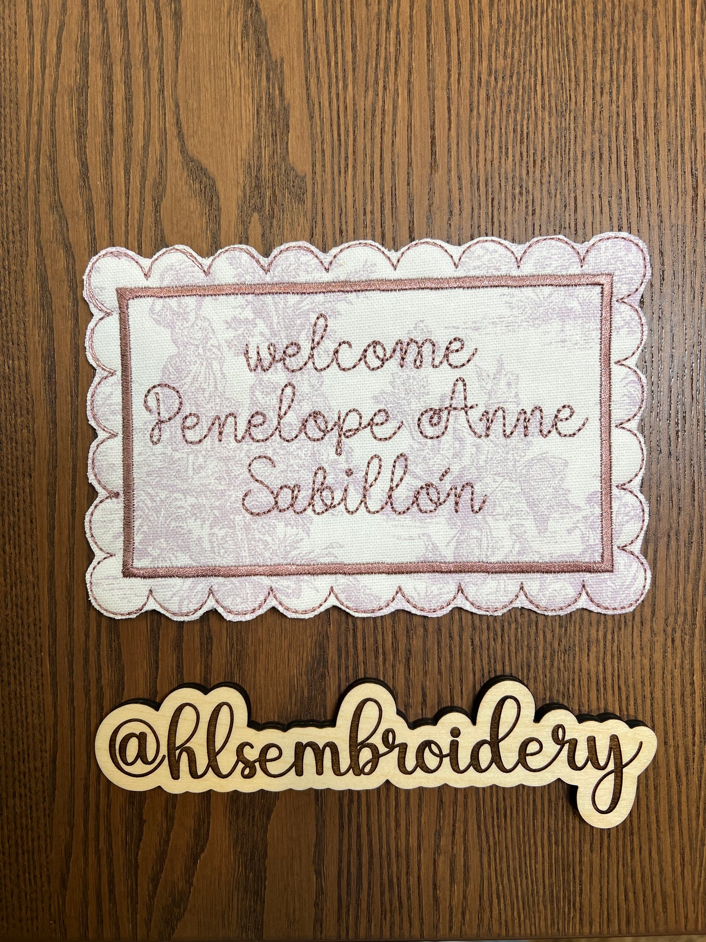 Embroidered nameplate with scalloped edge on a stand, featuring embroidery