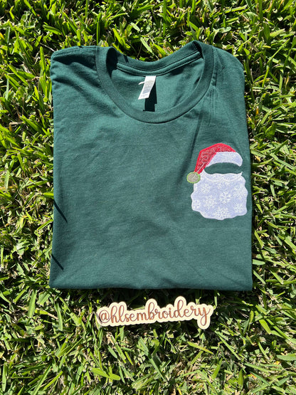 Green t-shirt with a Santa Claus design on grass, featuring the brand 'hlisembroidery'.