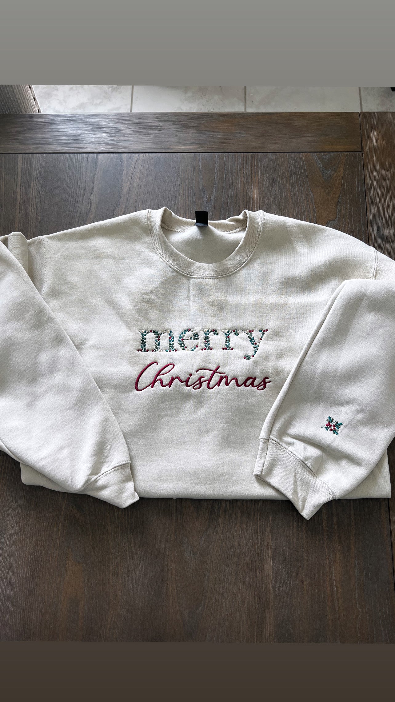 Sand sweatshirt with 'merry Christmas' text on a wooden surface