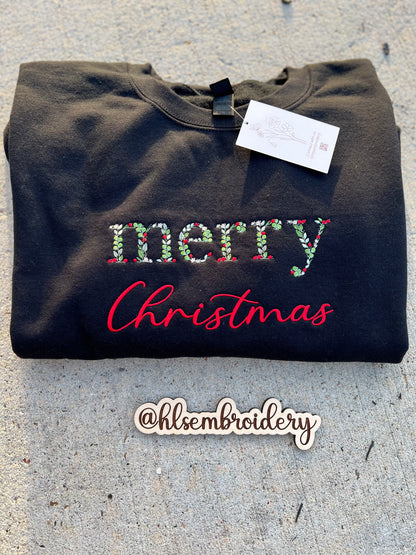 Black sweatshirt with 'Merry Christmas' embroidery on a concrete surface, 