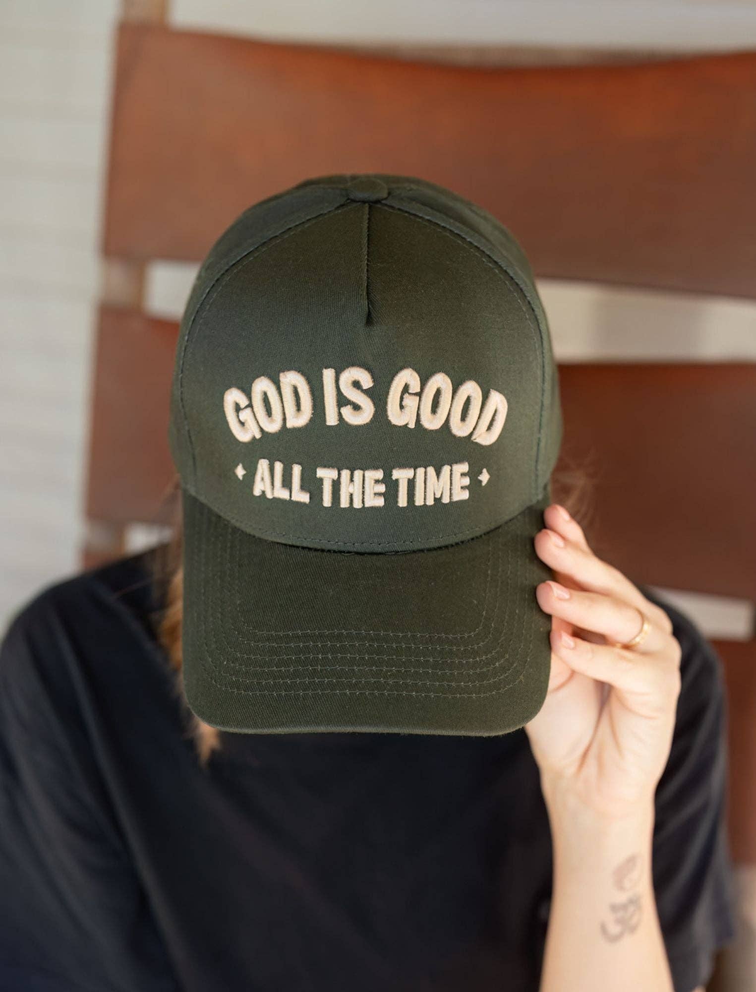 Person wearing a green cap with 'God is Good All the Time' text.
