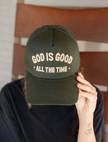 Person wearing a green cap with 'God is Good All the Time' text.