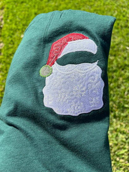 Green t-shirt with a Santa Claus design on grass, featuring the brand 'hlisembroidery'.