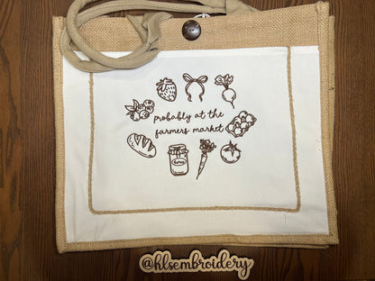 Embroidered bag with farmer's market-themed designs on a wooden surface