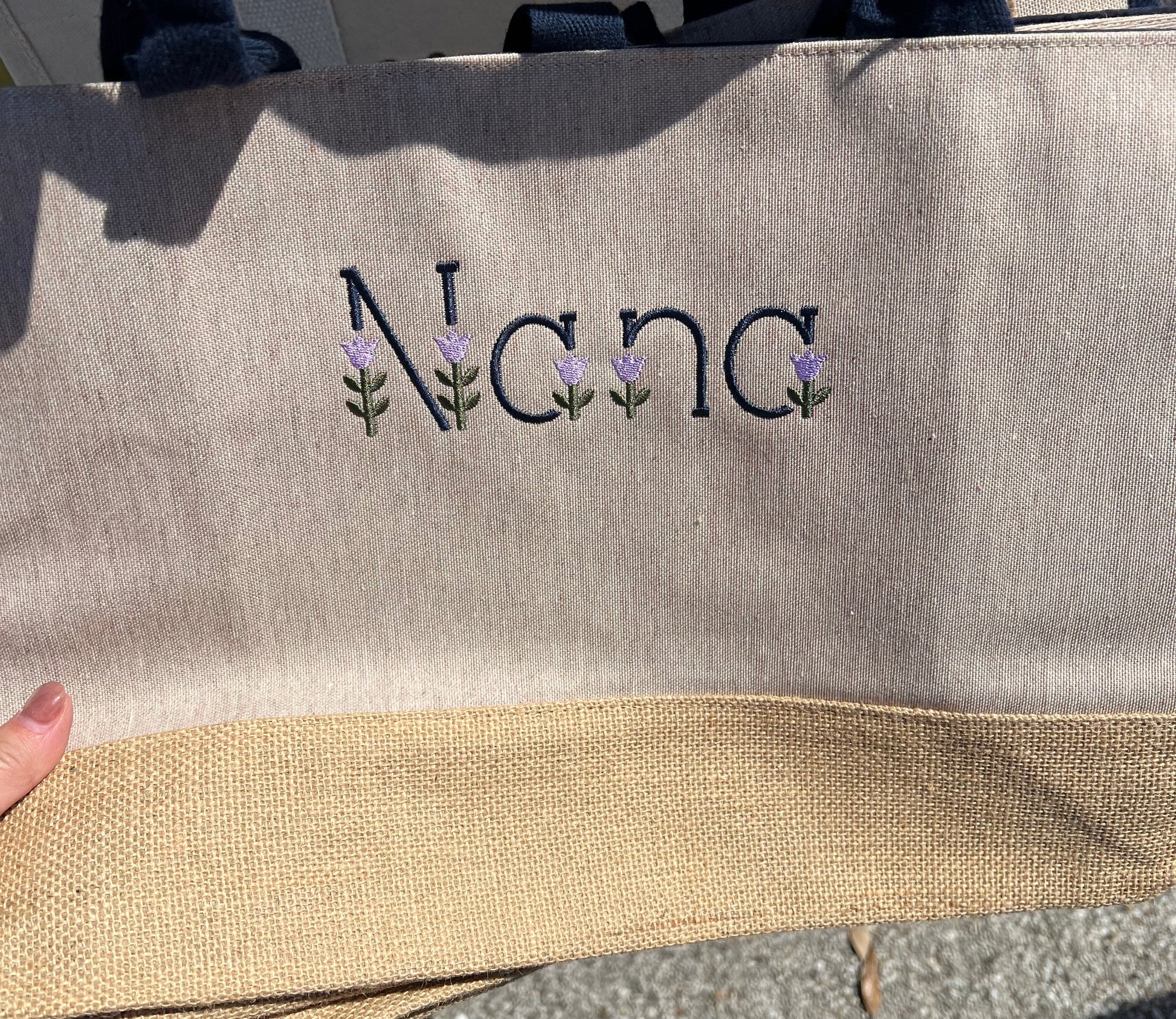 Nana wording in tulip embroidery font on the front of the tote bag