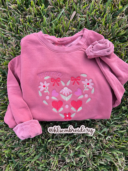 Comfort Colors Crewneck color Crimson with floral designs machine embroidered crosspoint heart with the text mama on the curve of the heart.