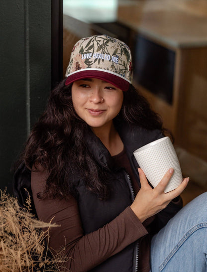 Person wearing a cap with floral patterns and 'Love healed me' text.