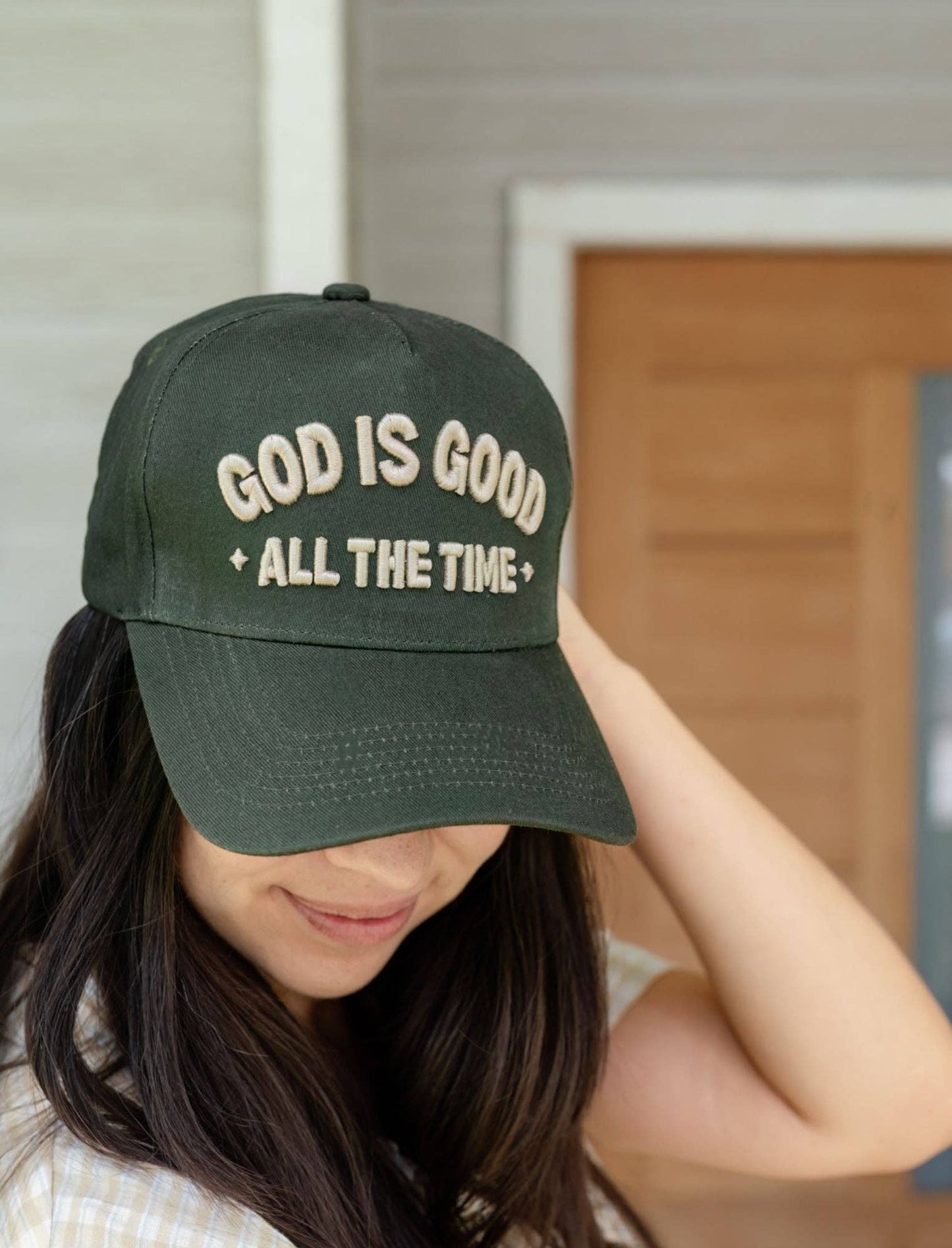 Person wearing a green cap with 'God is Good All the Time' text.
