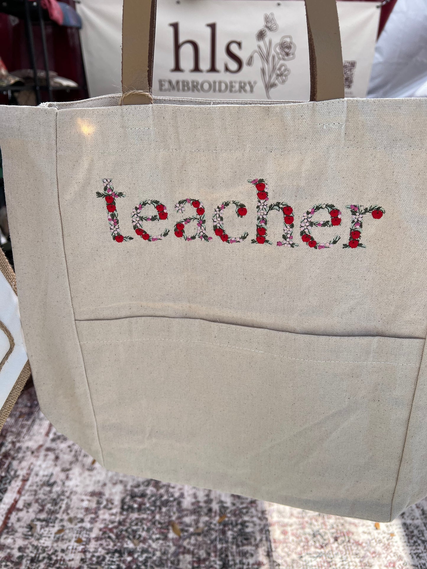 Teacher in Floral /Apple Font embroidered  on the front of a tote bag
