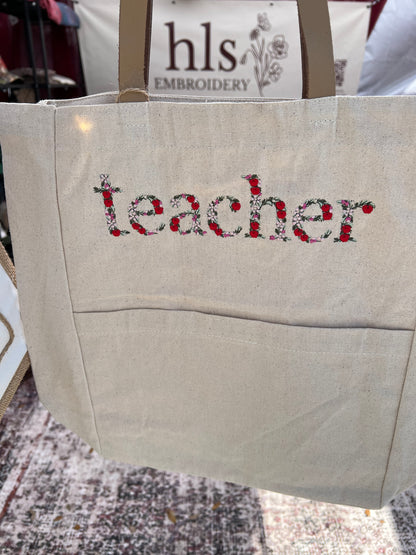 Teacher in Floral /Apple Font embroidered  on the front of a tote bag