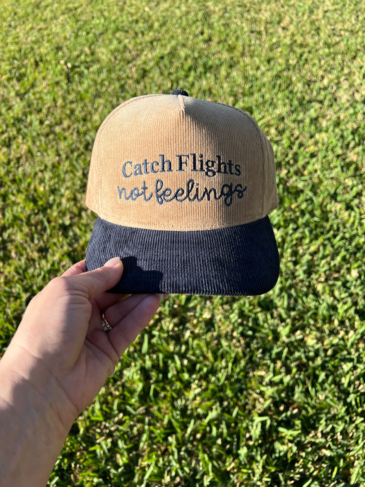 Beige and navy corduroy cap with embroidered text "catch flights not feelings"
