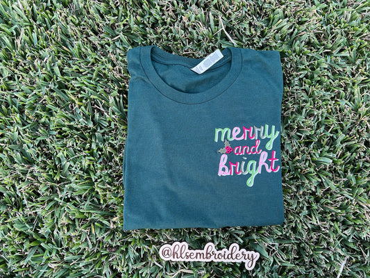 Folded shirt with 'merry and bright' text on grass
