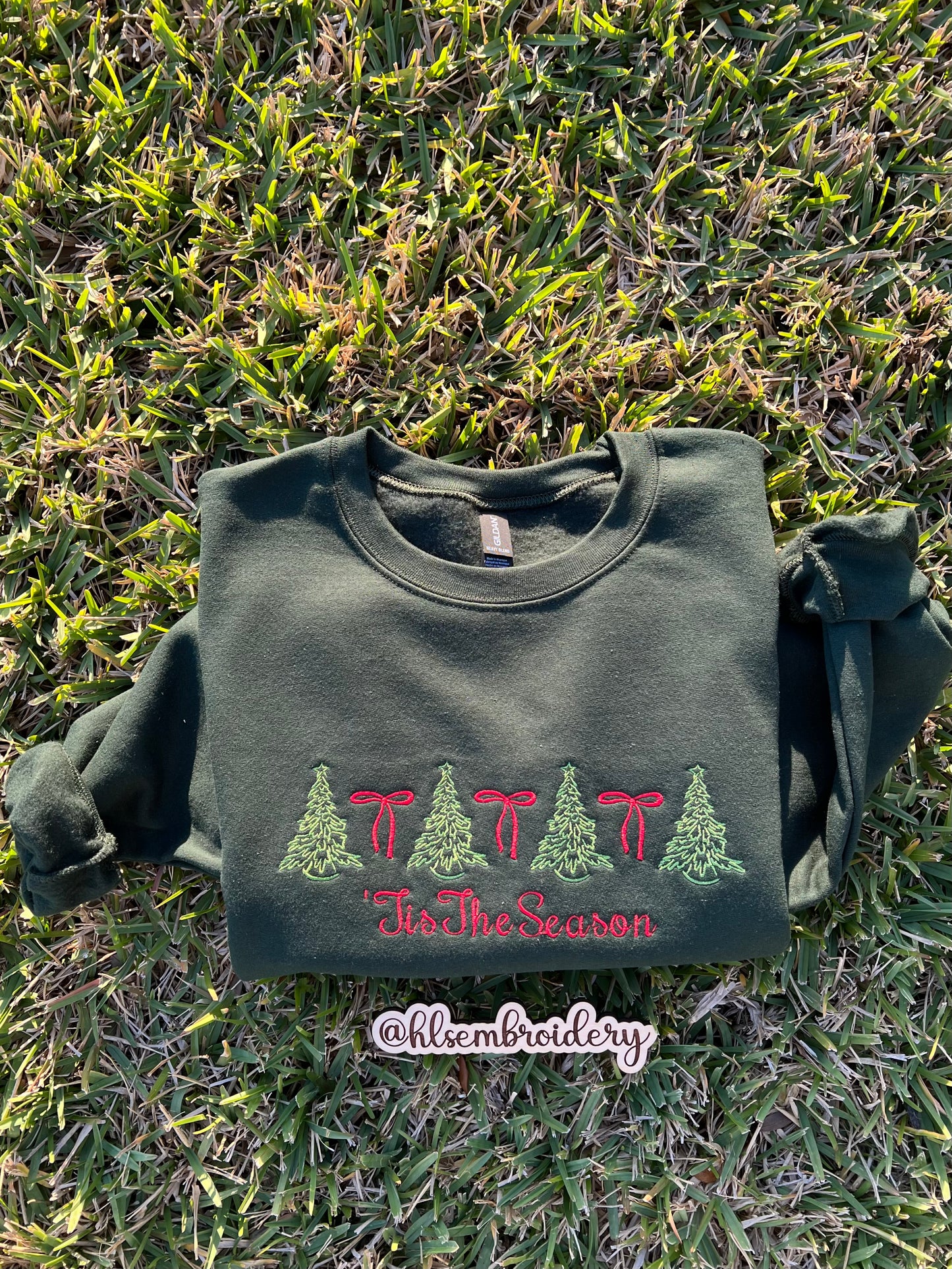 Green sweatshirt with embroidered design on grass