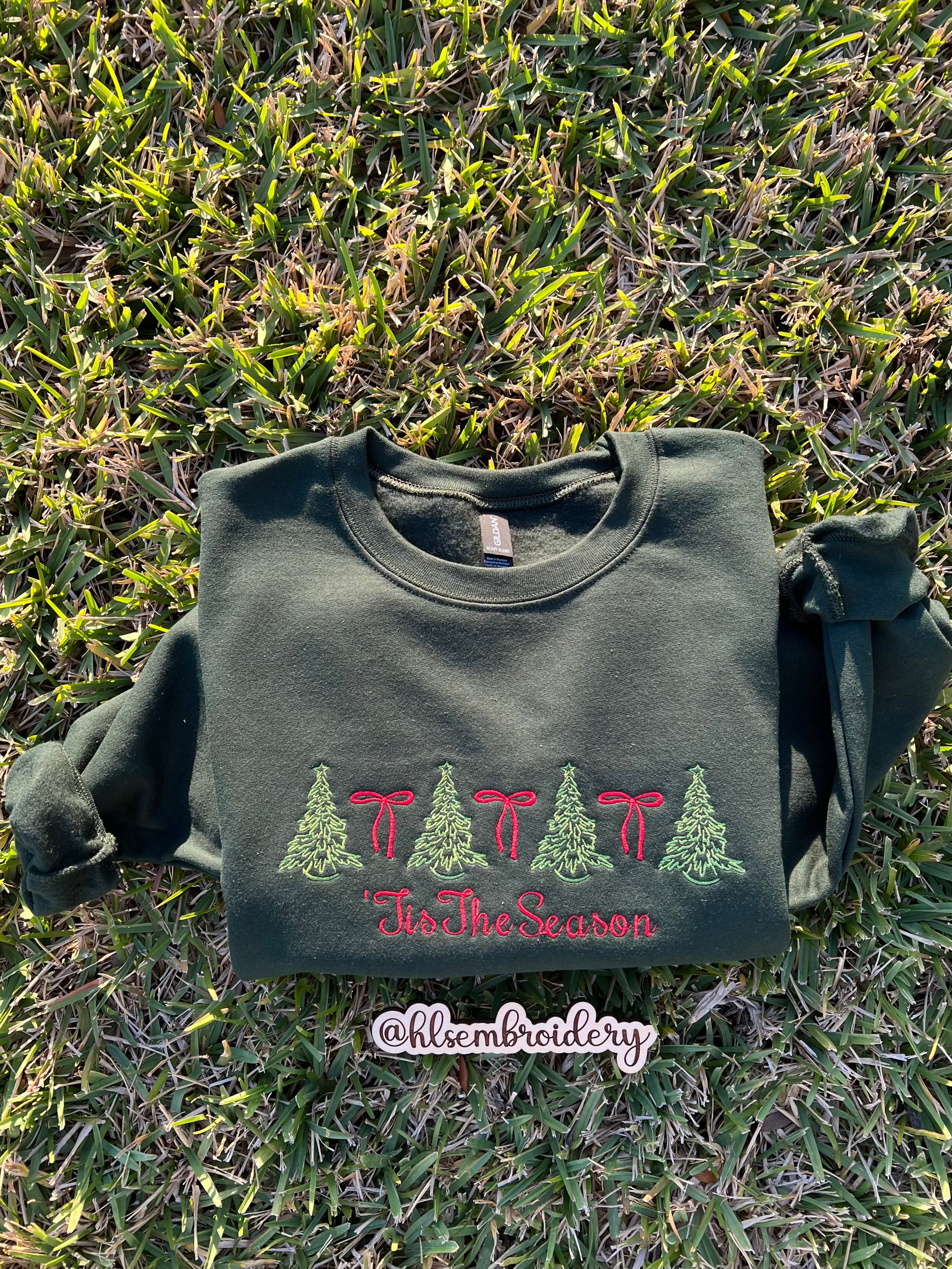 Green sweatshirt with embroidered design on grass