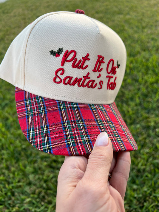 beige and plaid cap with the embroidery text on the front "put it on Santa's tab"