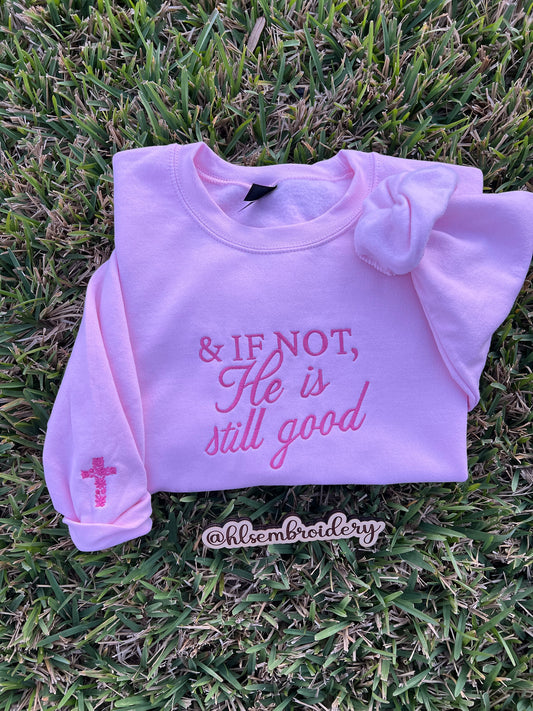 light Pink Gildan Crewneck with darker pink embroidered text "& if not, he is still good and a floral cross design on the sleeve. 