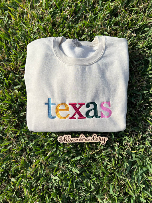 Sand color sweatshirt with 'texas' in colorful letters embroidered