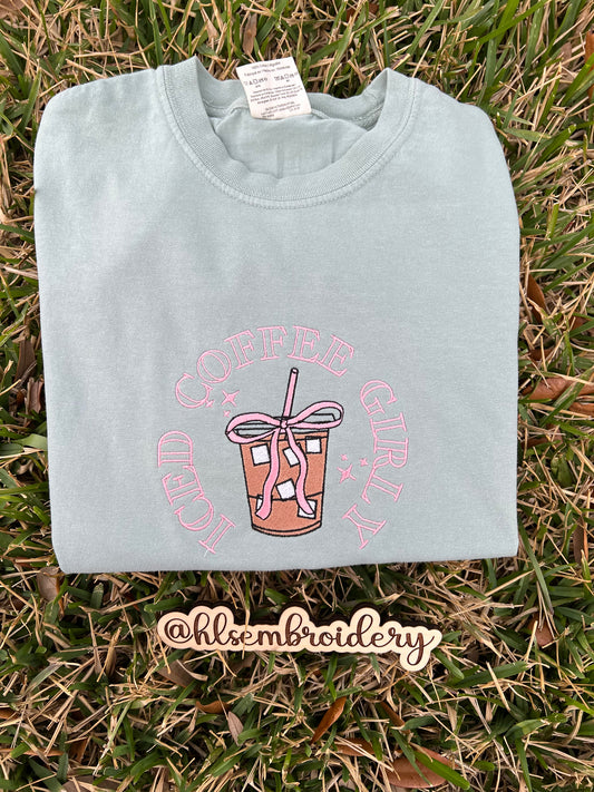 Light green t-shirt with pink graphic embroidery on grass,