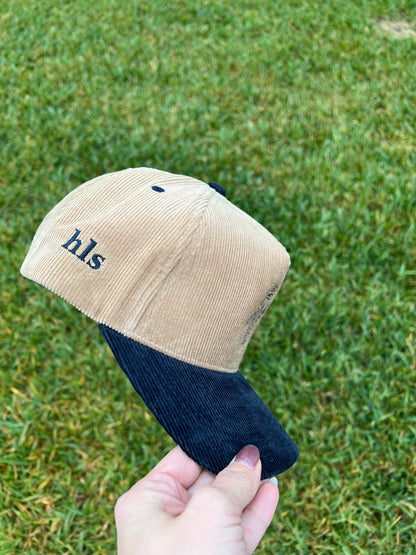 initials embroidered on side of beige/navy corduroy hat 