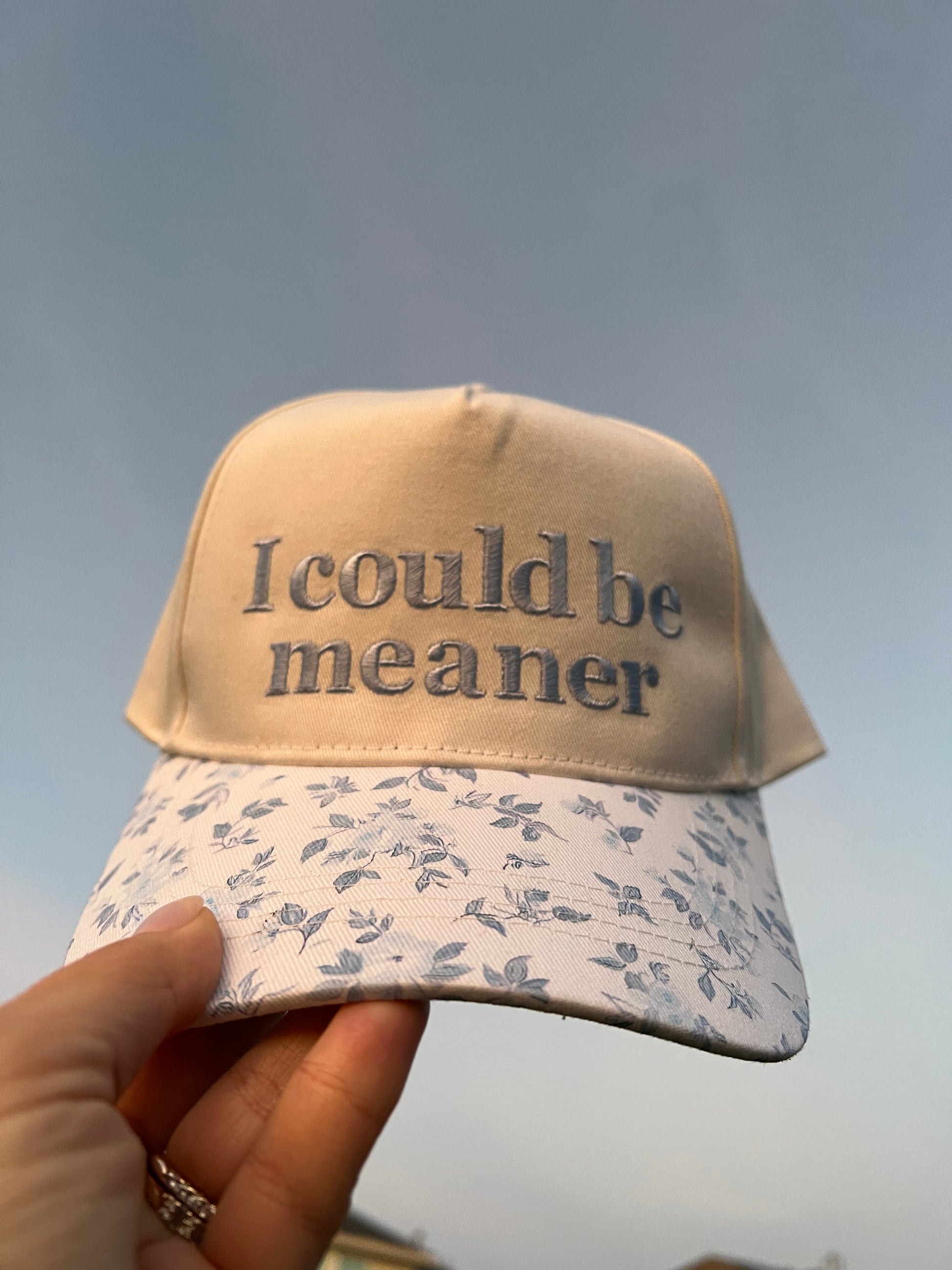 Cap with 'I could be meaner' text on a grass background