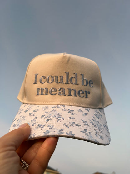 Cap with 'I could be meaner' text on a grass background