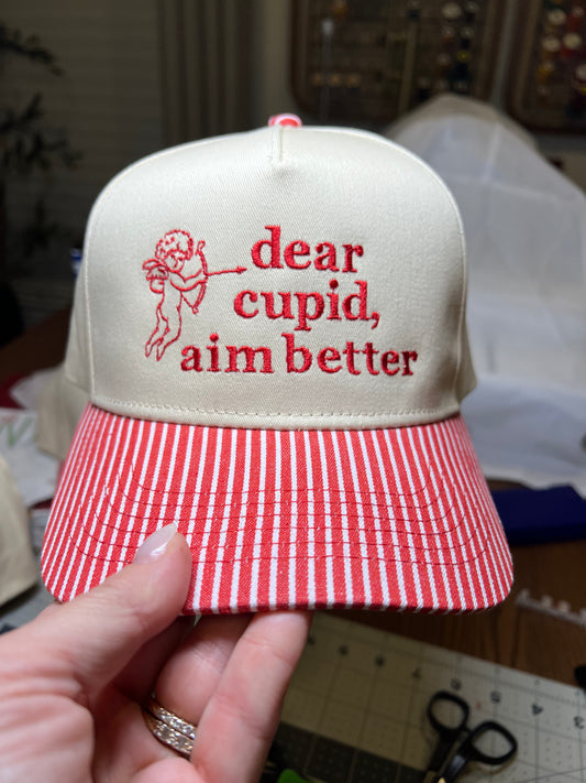red and white stripe brim with beige Cap with 'dear cupid, aim better' text embroidered 