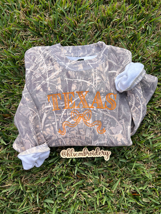 Camo crewneck with the word 'TEXAS' and a bow embroidered in orange