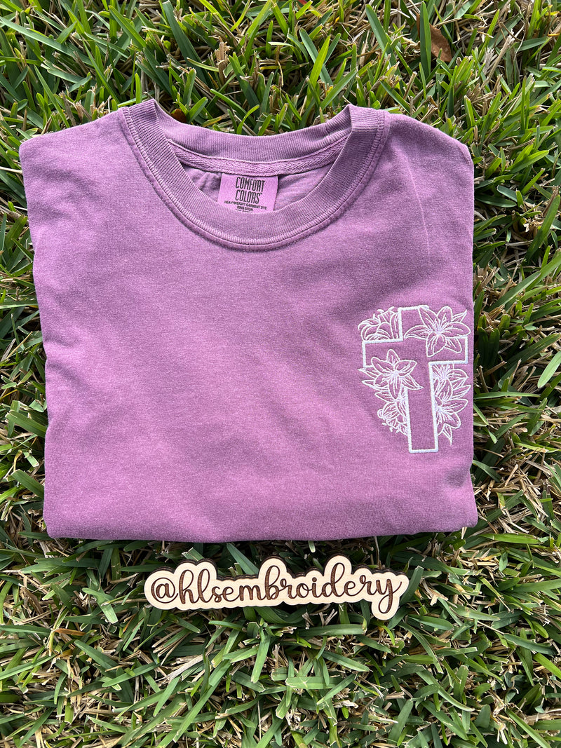  Comfort colors shirt berry with white floral cross design embroidered on it.