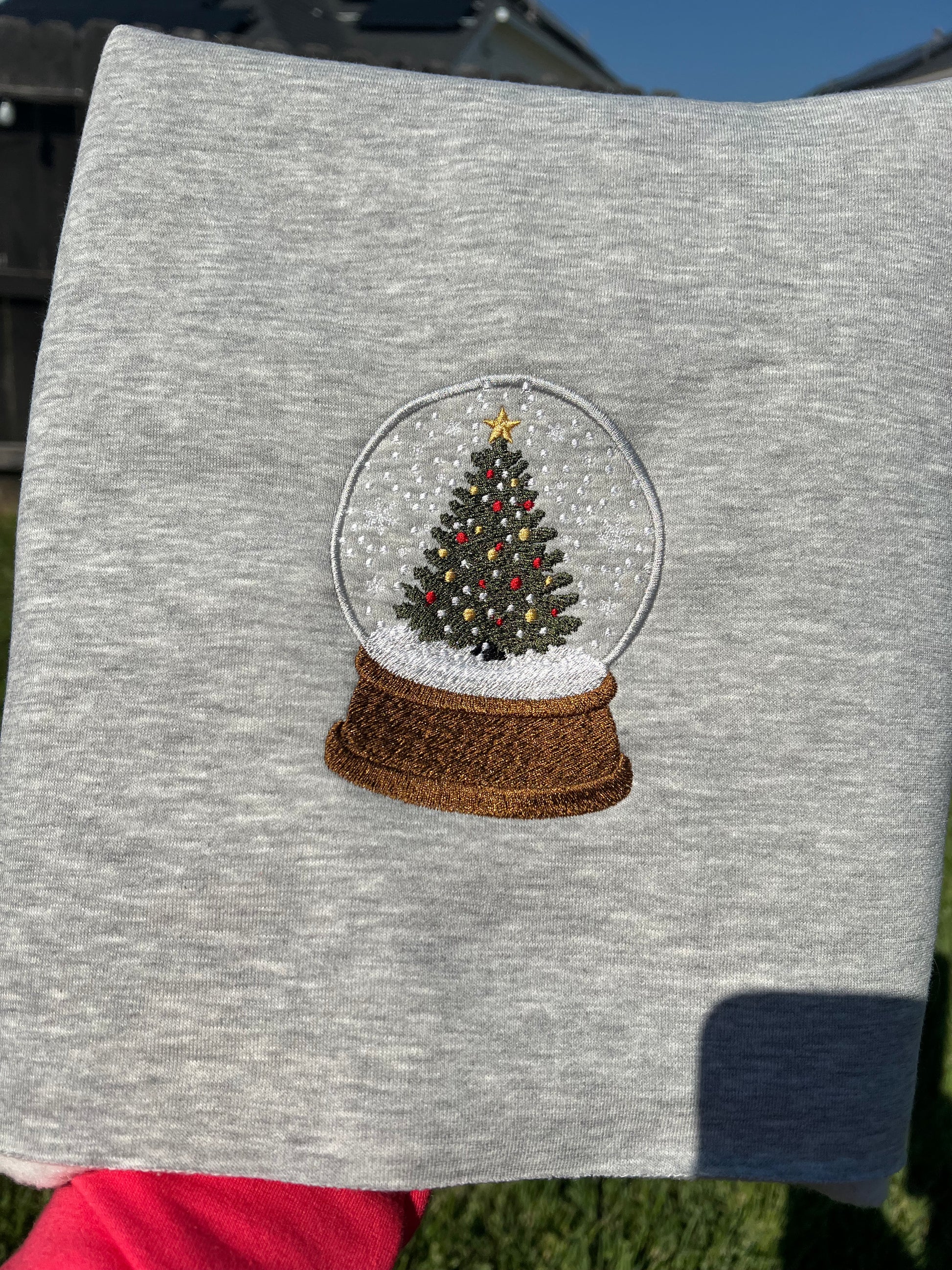 Gray sweatshirt with a Christmas tree snow globe design on a gray background