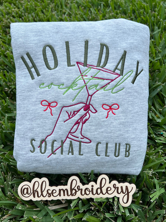 Embroidered sweatshirt with 'Holiday Cocktail Social Club' design on grass, featuring the brand '@hlsembroidery'.