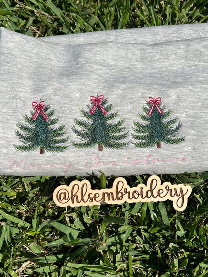 Embroidered Christmas trees with ribbons on a gray fabric background, with 'hlsembroidery' branding.