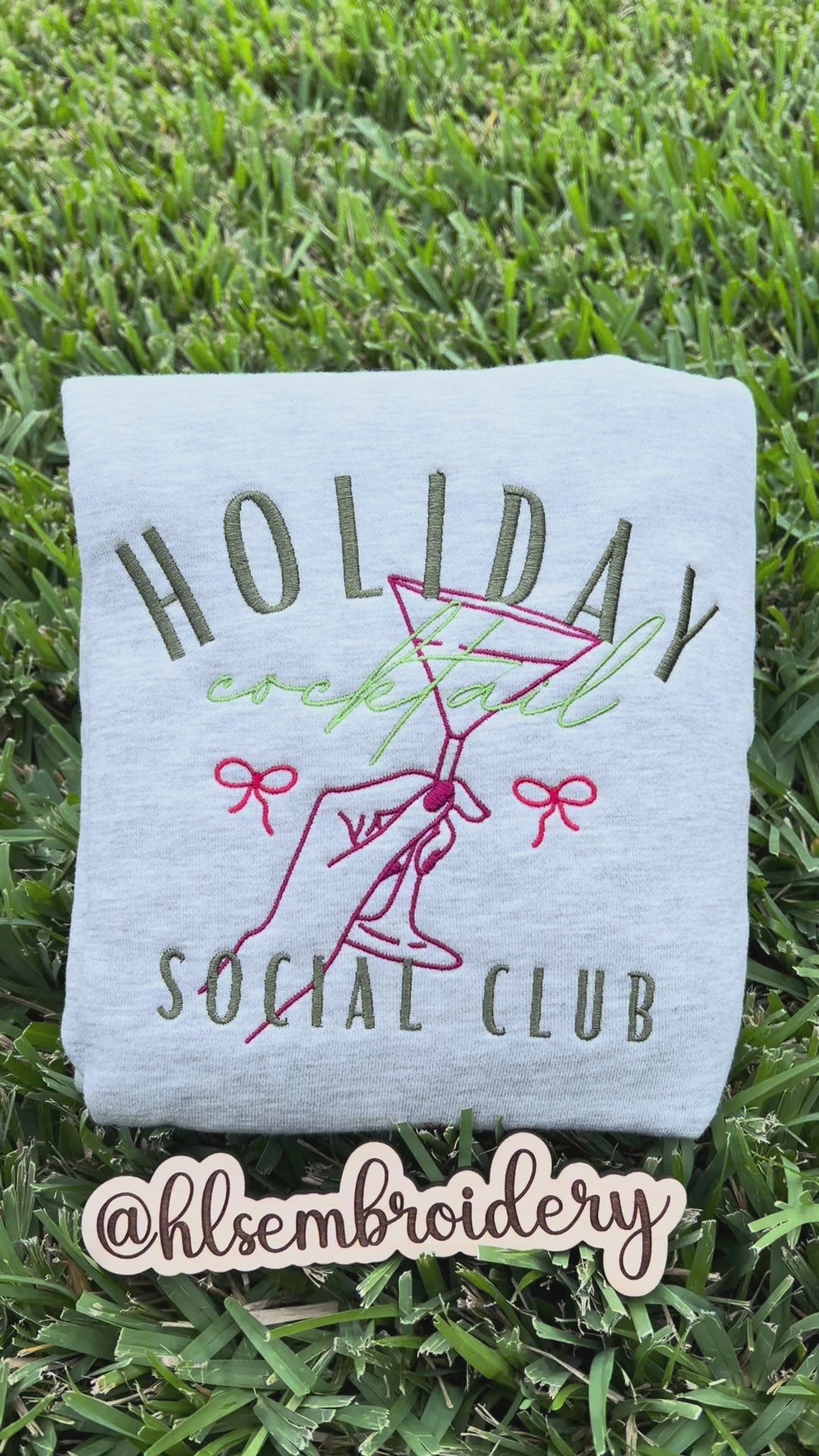 Embroidered sweatshirt with 'Holiday Cocktail Social Club' design on grass
