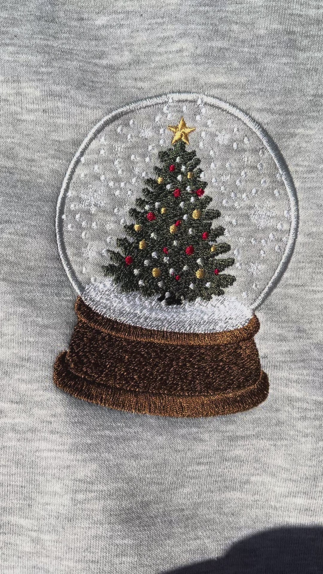 Gray sweatshirt with a Christmas tree snow globe design on a gray background