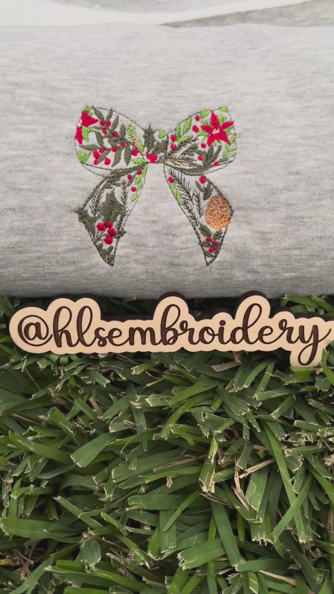 Embroidered bow design on a gray fabric with 'hlsembrodiery' branding.