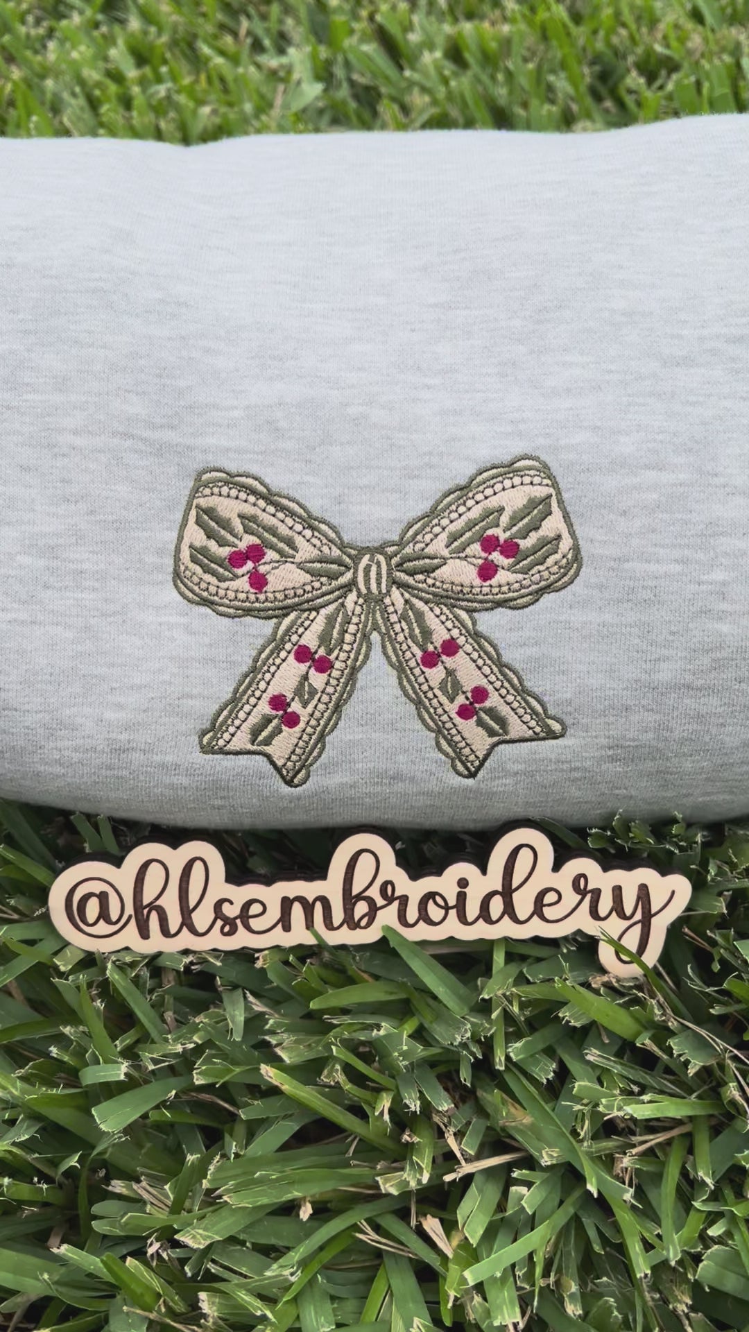 Embroidered bow design on a gray fabric with 'hlsembrodiery' branding.
