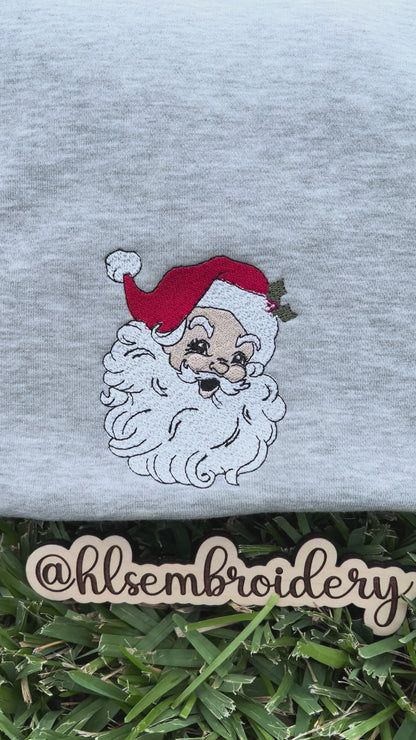 Gray sweatshirt with embroidered Santa Claus face on grass, featuring the brand hlsembroidery