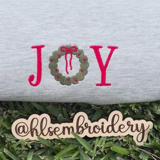 gray sweatshirt with 'JOY' and a wreath design 