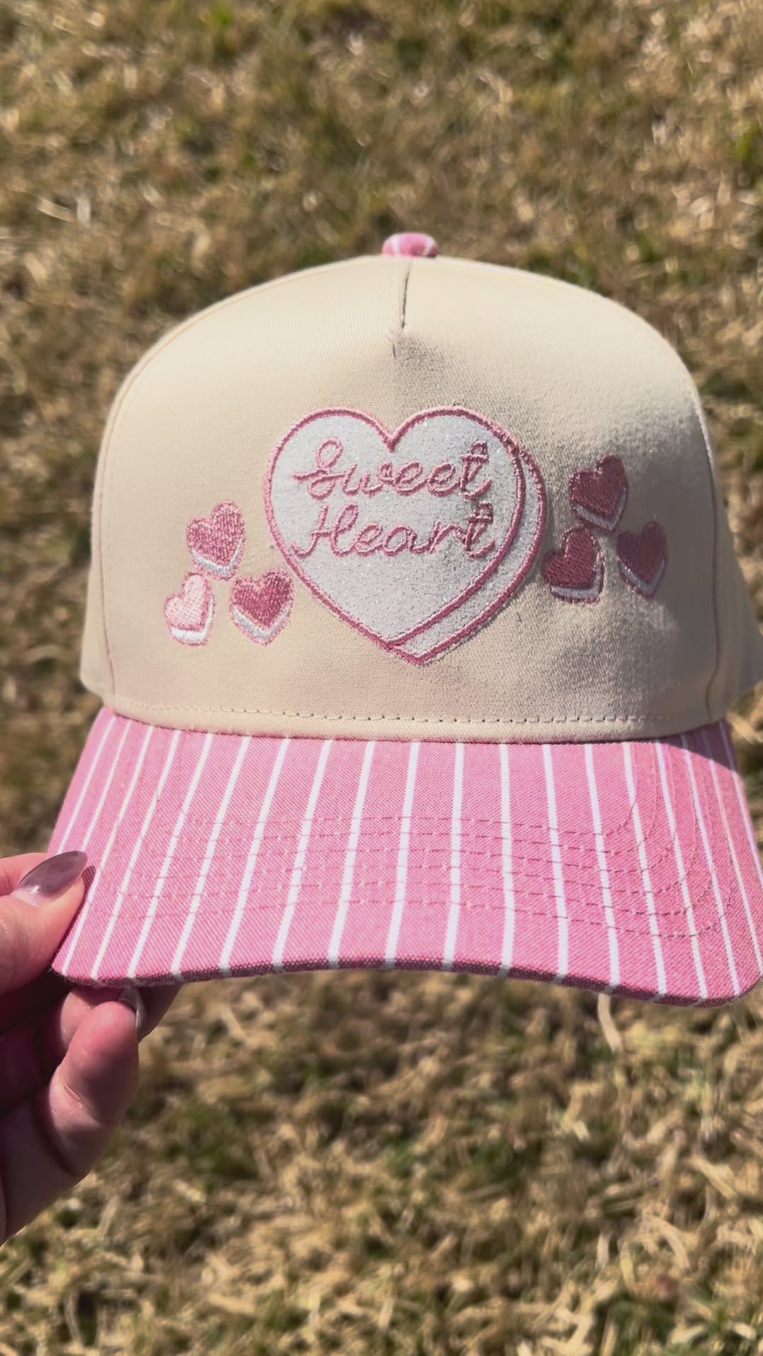 Sweet heart cap with pink and white stripped brim on grass background