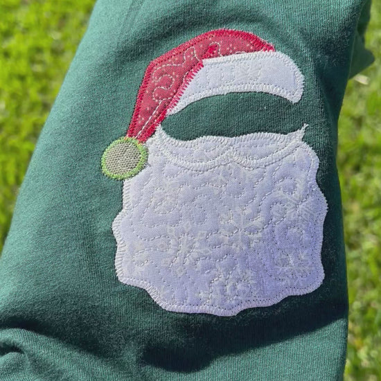 Green t-shirt with a Santa Claus design on grass, featuring the brand 'hlisembroidery'.