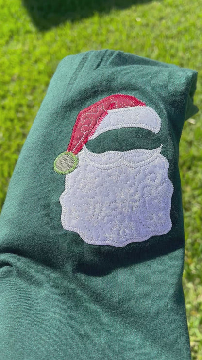 Green t-shirt with a Santa Claus design on grass, featuring the brand 'hlisembroidery'.